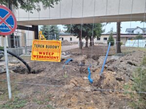 Tablica WSTĘP WZBRONIONY Plac budowy BCU, na placu maszyny budowlane pracownicy wykonujące prace ziemne