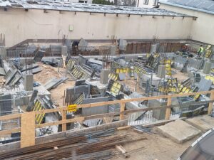 Plac budowy BCU. Pracujące maszyny pracownicy, Widać fundamenty budynku