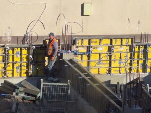 Plac budowy BCU. Pracujące maszyny pracownicy, Widać fundamenty budynku