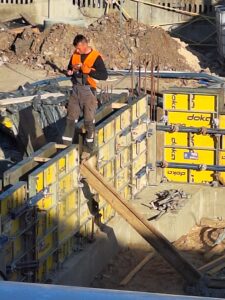 Plac budowy BCU. Pracujące maszyny pracownicy, Widać fundamenty budynku