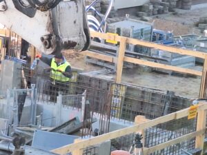 Plac budowy BCU. Pracujące maszyny pracownicy, Widać fundamenty budynku