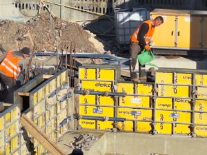Plac budowy BCU. Pracujące maszyny pracownicy, Widać fundamenty budynku