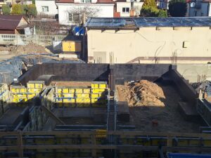 Plac budowy BCU. Pracujące maszyny pracownicy, Widać fundamenty budynku