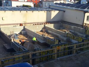 Plac budowy BCU. Pracujące maszyny pracownicy, Widać fundamenty budynku