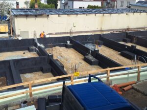 Plac budowy BCU. Pracujące maszyny pracownicy, Widać fundamenty budynku