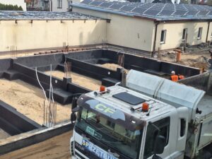 Plac budowy BCU. Pracujące maszyny pracownicy, Widać fundamenty budynku