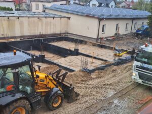 Plac budowy BCU. Pracujące maszyny pracownicy, Widać fundamenty budynku