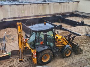 Plac budowy BCU. Pracujące maszyny pracownicy, Widać fundamenty budynku