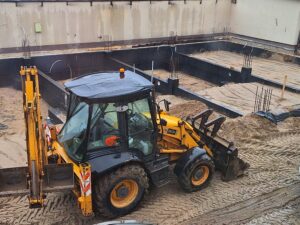 Plac budowy BCU. Pracujące maszyny pracownicy, Widać fundamenty budynku