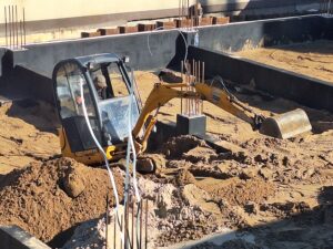 Plac budowy BCU. Pracujące maszyny pracownicy, Widać fundamenty budynku