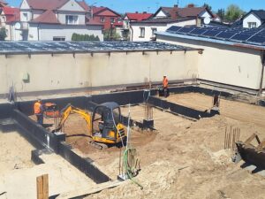 Plac budowy BCU. Pracujące maszyny pracownicy, Widać fundamenty budynku