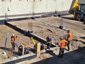 Plac budowy BCU. Pracujące maszyny pracownicy, Widać fundamenty budynku