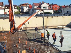 Plac budowy BCU. Pracujące maszyny pracownicy, Widać kolejny etap prac budowlanych (zalewanie filarów)