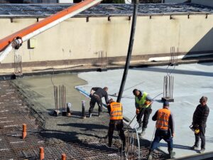 Plac budowy BCU. Pracujące maszyny pracownicy, Widać kolejny etap prac budowlanych (zalewanie filarów)