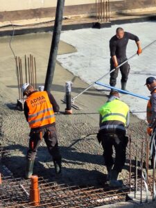Plac budowy BCU. Pracujące maszyny pracownicy, Widać kolejny etap prac budowlanych (zalewanie filarów)
