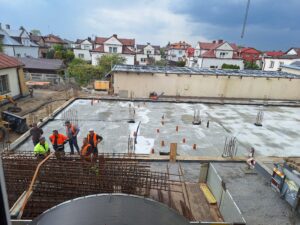 Plac budowy BCU. Pracujące maszyny pracownicy, Widać kolejny etap prac budowlanych (zalewanie filarów)