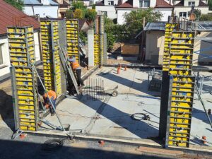 Plac budowy BCU. Pracujące maszyny pracownicy, Widać kolejny etap prac budowlanych (zalewanie filarów)